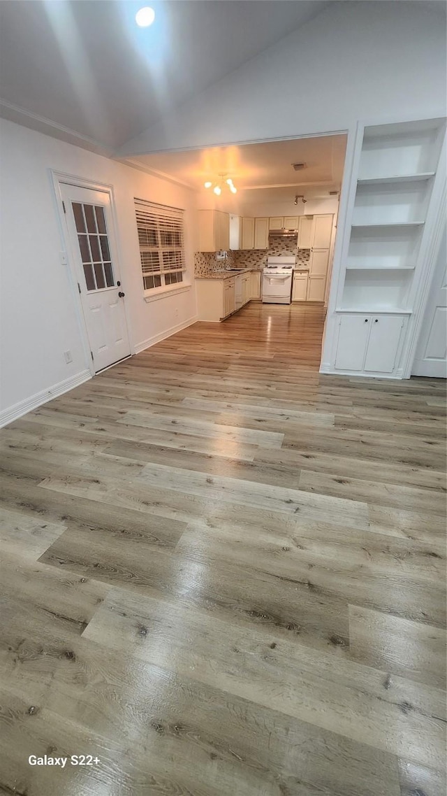 interior space featuring baseboards, a sink, vaulted ceiling, and light wood finished floors