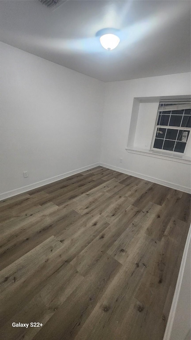 spare room with dark wood-style floors and baseboards