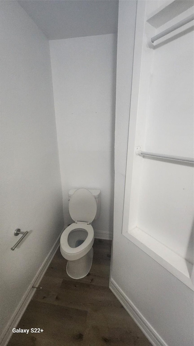 bathroom with toilet, baseboards, and wood finished floors