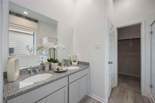 bathroom featuring wood-type flooring, a shower with shower door, and vanity