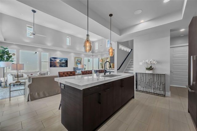 kitchen featuring pendant lighting, sink, a breakfast bar area, dark brown cabinetry, and a center island with sink