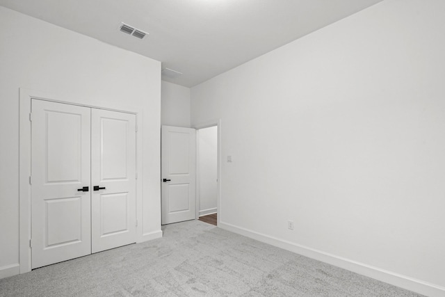 unfurnished bedroom with a closet and light carpet