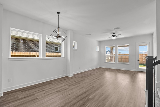 spare room featuring ceiling fan with notable chandelier and hardwood / wood-style floors