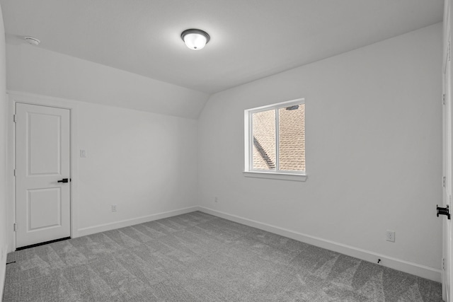 additional living space featuring vaulted ceiling and light colored carpet