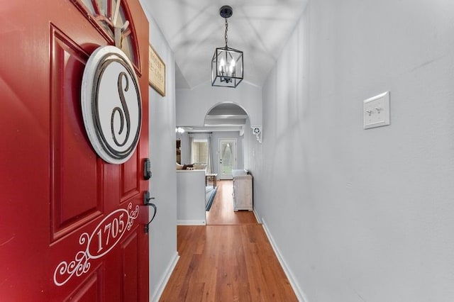 entrance foyer with an inviting chandelier, wood-type flooring, and vaulted ceiling