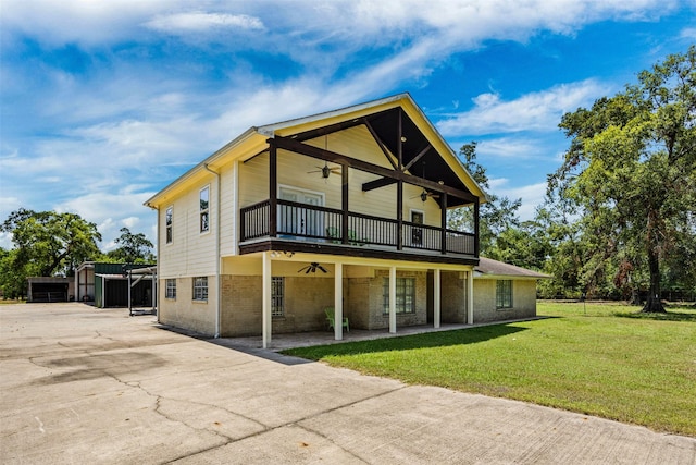 back of property with a lawn, a balcony, and ceiling fan