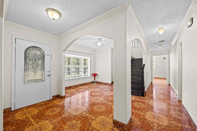 foyer entrance with ornamental molding, ceiling fan, and a textured ceiling