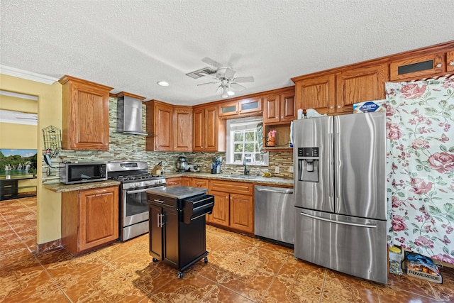 kitchen featuring appliances with stainless steel finishes, sink, decorative backsplash, a center island, and wall chimney range hood