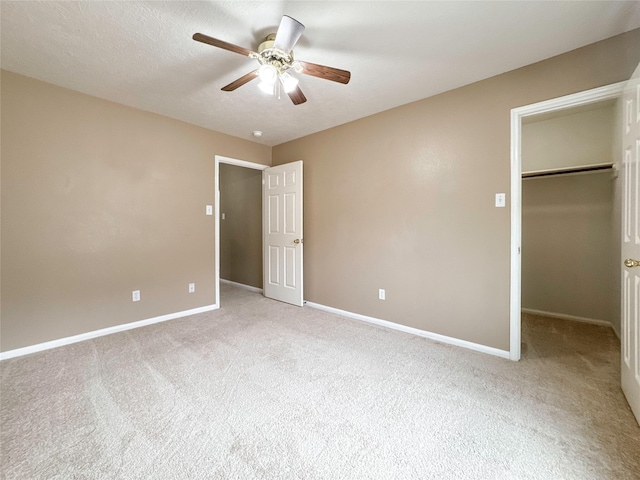 unfurnished bedroom with a walk in closet, light colored carpet, ceiling fan, a textured ceiling, and a closet
