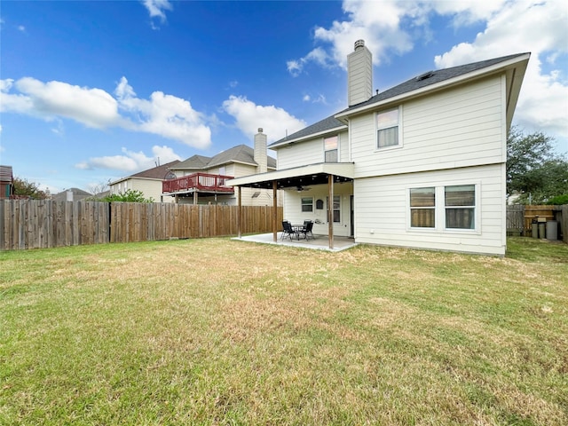 rear view of property with ceiling fan, a yard, and a patio area