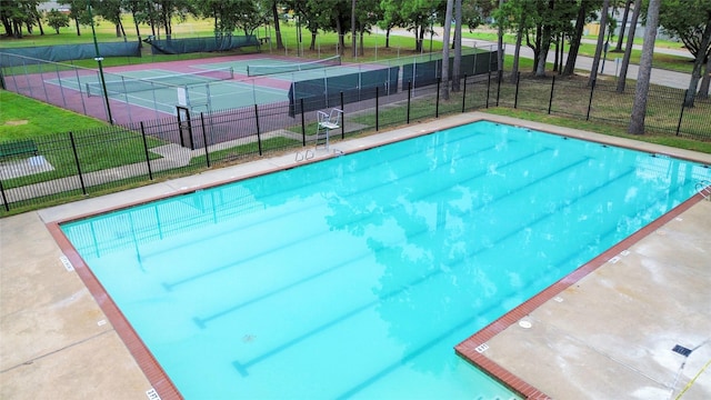 view of swimming pool with a yard and tennis court