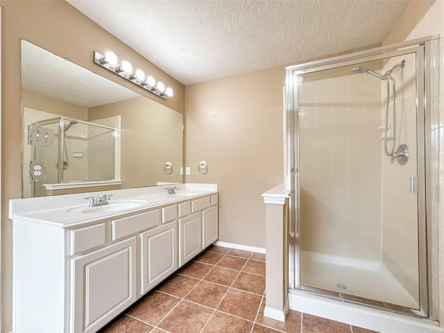bathroom featuring tile patterned floors, a shower with door, a textured ceiling, and vanity