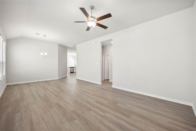 unfurnished living room featuring vaulted ceiling, light wood-style flooring, baseboards, and ceiling fan with notable chandelier