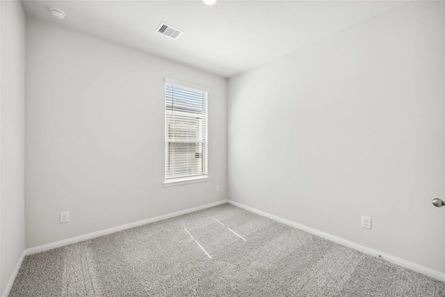 spare room featuring carpet floors, visible vents, and baseboards