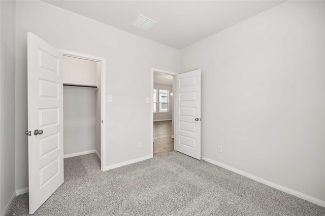 unfurnished bedroom featuring carpet floors, a spacious closet, a closet, and baseboards