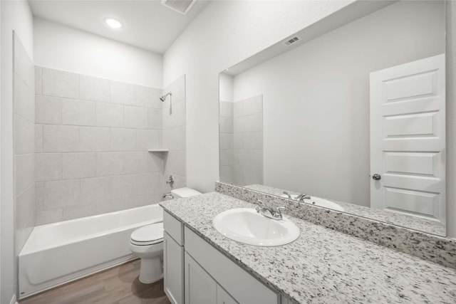 full bath with visible vents, toilet, wood finished floors, vanity, and shower / bathing tub combination