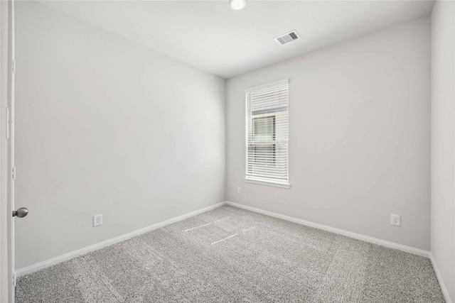 empty room with carpet flooring, visible vents, and baseboards