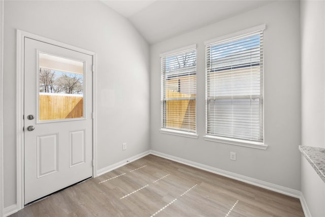 interior space featuring vaulted ceiling, light wood finished floors, and baseboards