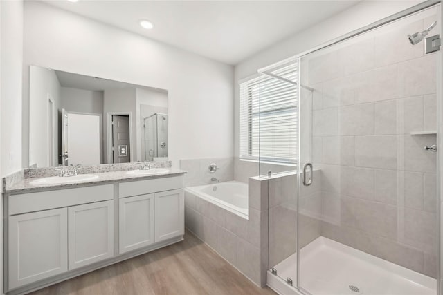 bathroom with a stall shower, wood finished floors, a sink, and a bath