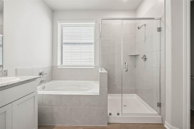 bathroom featuring a stall shower, a garden tub, and vanity