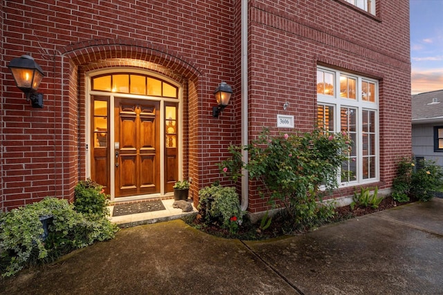 exterior entry at dusk featuring brick siding