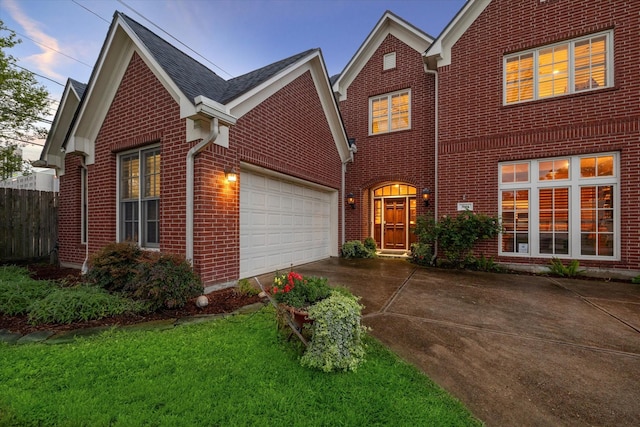 traditional home featuring brick siding, concrete driveway, an attached garage, fence, and a front lawn