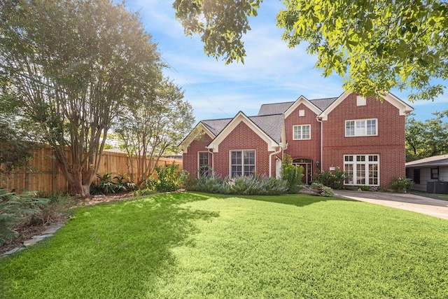 traditional home with a front yard, brick siding, fence, and central AC