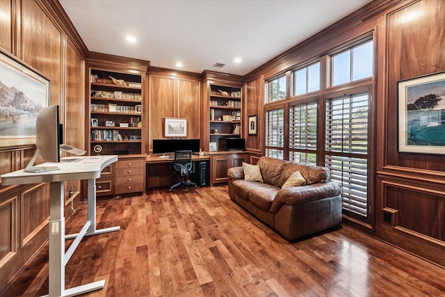 home office featuring built in shelves, visible vents, and wood finished floors