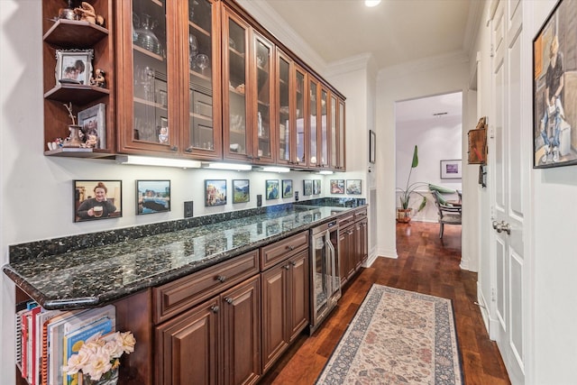 kitchen featuring beverage cooler, ornamental molding, dark stone counters, dark wood finished floors, and glass insert cabinets