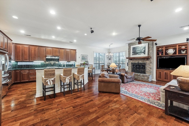 kitchen with a center island, dark wood-style flooring, open floor plan, under cabinet range hood, and a kitchen breakfast bar