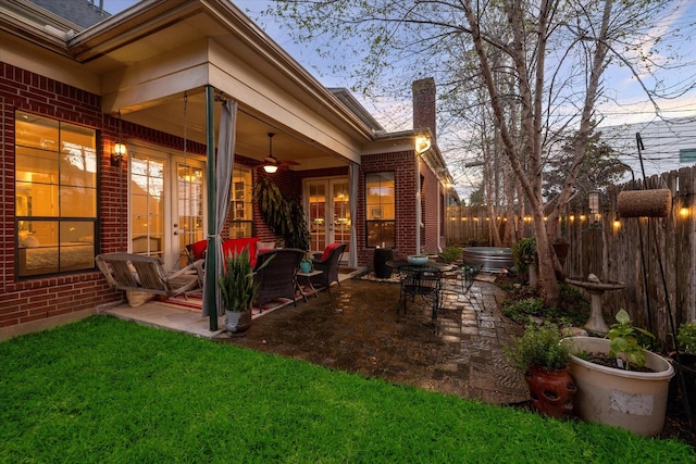 exterior space featuring french doors, brick siding, a patio, a ceiling fan, and fence