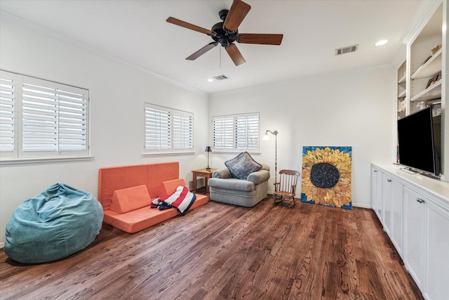 living area featuring crown molding, visible vents, ceiling fan, and wood finished floors