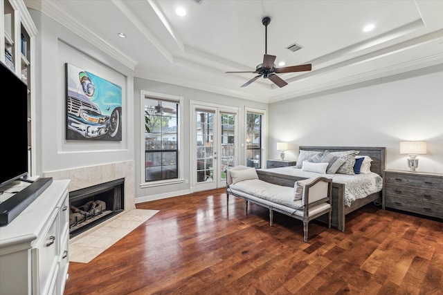 bedroom featuring dark wood-type flooring, a raised ceiling, visible vents, and a premium fireplace