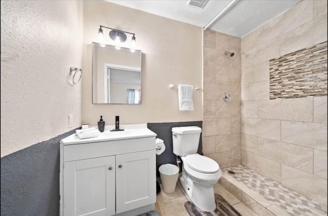 bathroom with vanity, a tile shower, tile patterned floors, and toilet