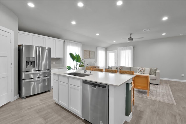 kitchen featuring white cabinetry, sink, stainless steel appliances, a center island with sink, and light wood-type flooring