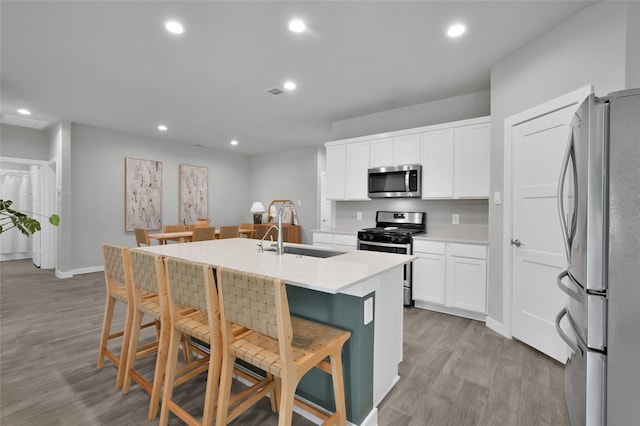 kitchen featuring sink, a breakfast bar area, appliances with stainless steel finishes, an island with sink, and white cabinets