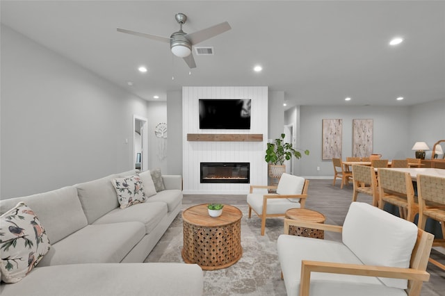 living room featuring light hardwood / wood-style floors, a large fireplace, and ceiling fan