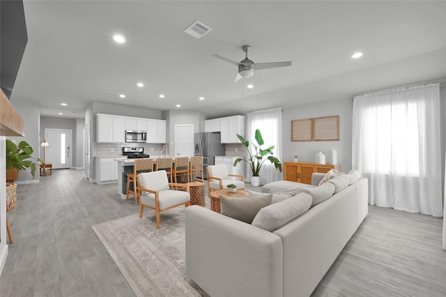 living room with plenty of natural light, light hardwood / wood-style floors, and ceiling fan