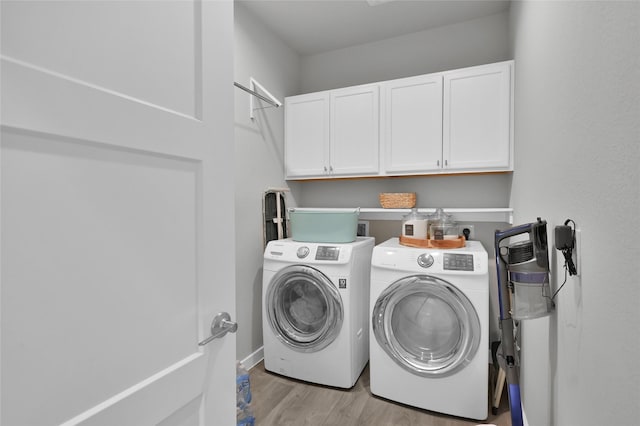 clothes washing area with cabinets, light hardwood / wood-style floors, and washing machine and dryer