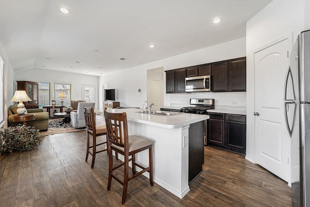 kitchen featuring appliances with stainless steel finishes, dark hardwood / wood-style floors, sink, dark brown cabinetry, and a center island with sink