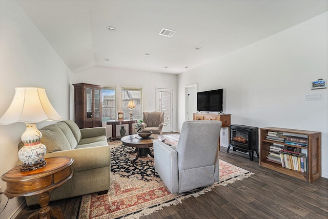 living room featuring lofted ceiling, dark hardwood / wood-style flooring, and a wood stove