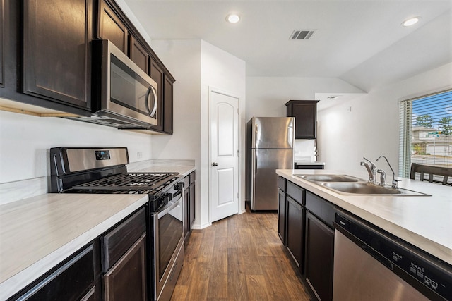 kitchen with appliances with stainless steel finishes, sink, dark wood-type flooring, and dark brown cabinets