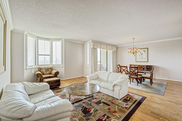 living room featuring wood-type flooring, ornamental molding, a notable chandelier, and a textured ceiling