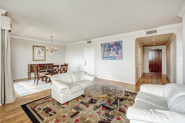 living room with crown molding, light hardwood / wood-style floors, a textured ceiling, and a notable chandelier