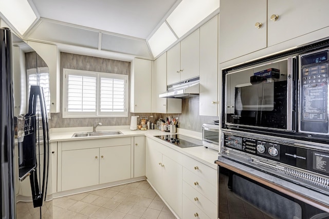 kitchen with backsplash, light tile patterned floors, sink, and black appliances