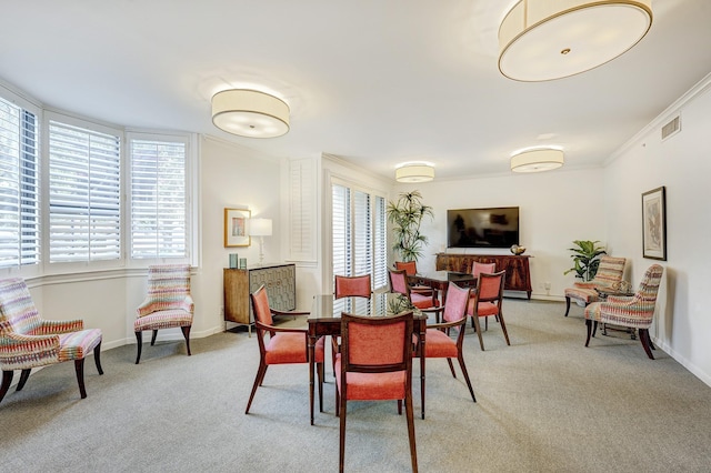 dining room with ornamental molding and light colored carpet