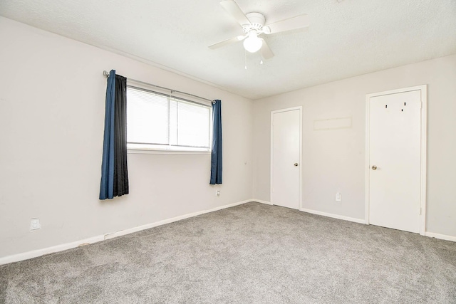 carpeted spare room featuring a textured ceiling, ceiling fan, and baseboards