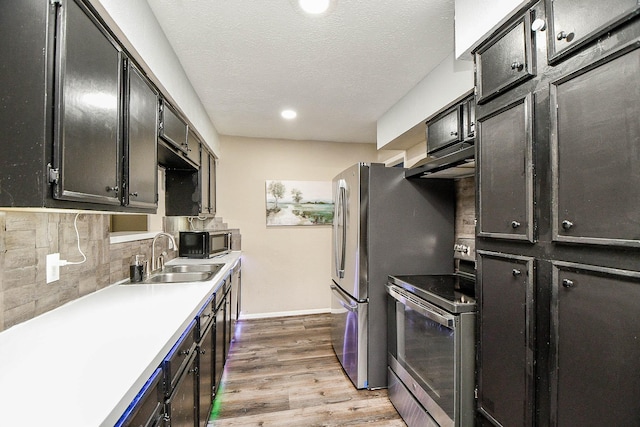 kitchen featuring electric stove, light countertops, light wood-style flooring, decorative backsplash, and a sink