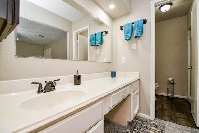 full bathroom with visible vents, toilet, vanity, wood finished floors, and baseboards