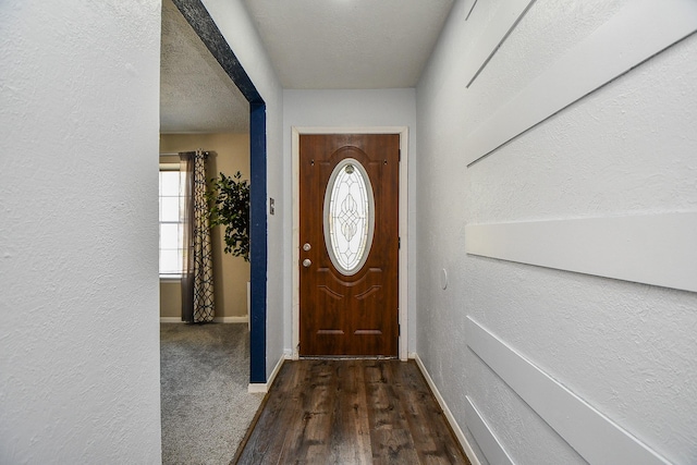 entryway featuring dark wood-style floors, a textured wall, a textured ceiling, and baseboards